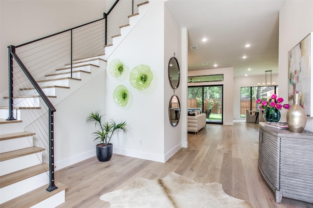 foyer featuring light wood-style floors, recessed lighting, baseboards, and stairs