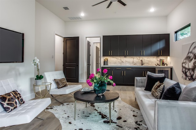 living room with beverage cooler, visible vents, and light wood-style flooring