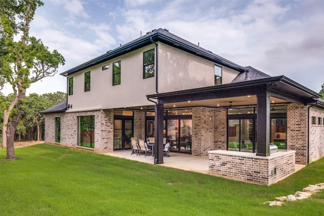 rear view of property with stucco siding, a patio area, brick siding, and a lawn