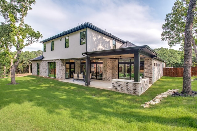 rear view of house featuring a patio area, a lawn, brick siding, and fence