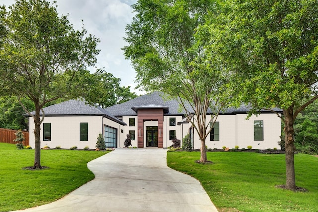 view of front of property featuring an attached garage, driveway, roof with shingles, and a front yard