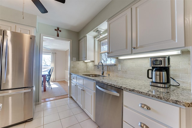 kitchen featuring appliances with stainless steel finishes, white cabinetry, sink, backsplash, and a healthy amount of sunlight