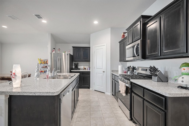 kitchen with a kitchen island with sink, sink, light tile patterned floors, and appliances with stainless steel finishes