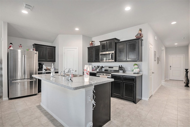 kitchen featuring sink, light tile patterned floors, stainless steel appliances, and a kitchen island with sink