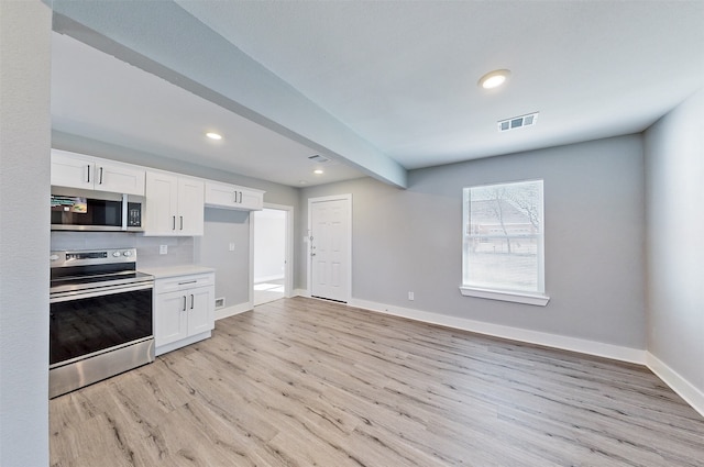 kitchen featuring backsplash, light hardwood / wood-style floors, white cabinetry, and stainless steel appliances