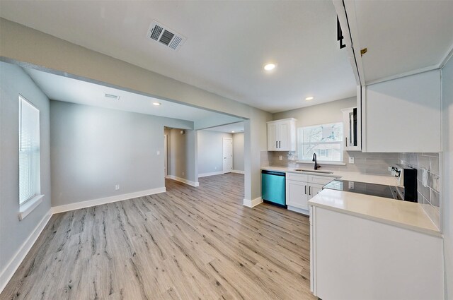 kitchen with sink, tasteful backsplash, appliances with stainless steel finishes, white cabinets, and light wood-type flooring