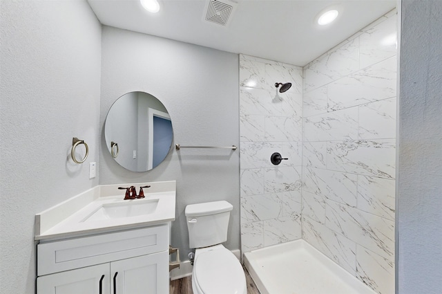 bathroom with vanity, toilet, and a tile shower