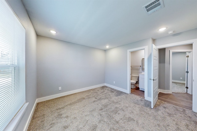 unfurnished bedroom with ensuite bathroom and light carpet