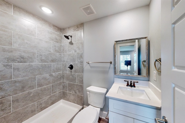 bathroom featuring vanity, toilet, and a tile shower