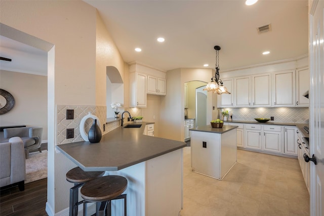 kitchen featuring hanging light fixtures, white cabinetry, a kitchen breakfast bar, and kitchen peninsula