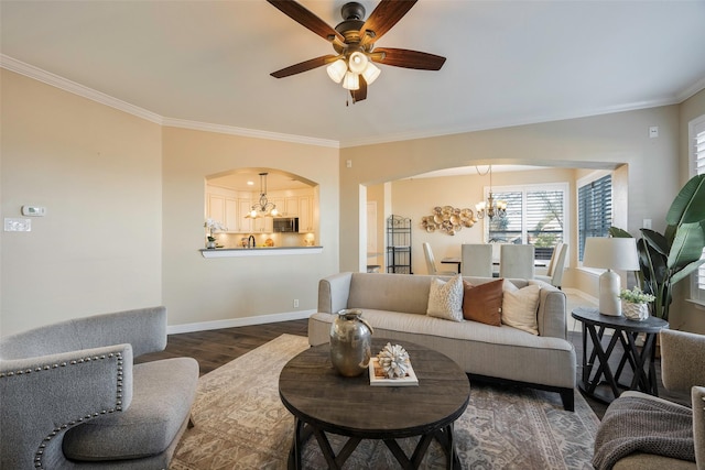 living room featuring dark hardwood / wood-style flooring, ceiling fan with notable chandelier, and ornamental molding