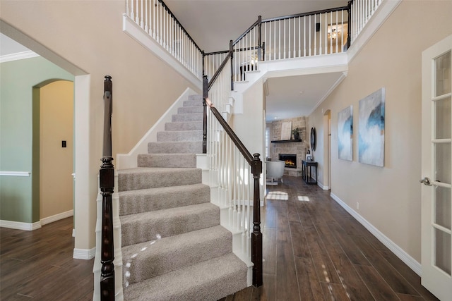 foyer featuring a towering ceiling, dark hardwood / wood-style floors, and a stone fireplace