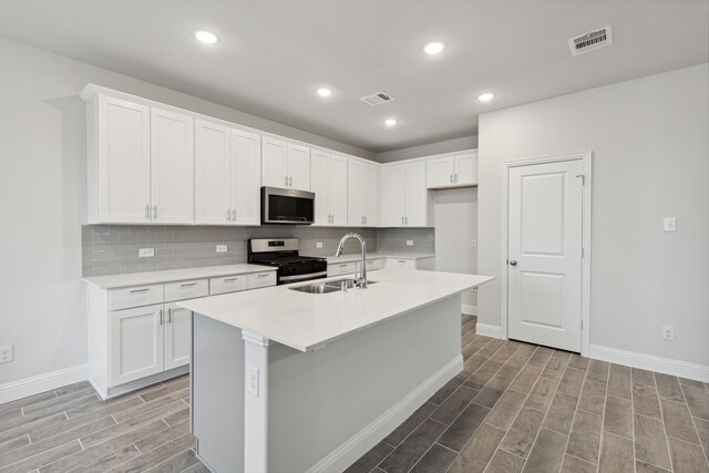 kitchen featuring white cabinetry, stainless steel appliances, and an island with sink