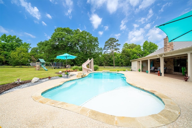 view of pool with a patio, a water slide, a playground, and a lawn