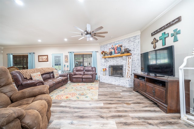 living room featuring a brick fireplace, ornamental molding, light hardwood / wood-style floors, and ceiling fan