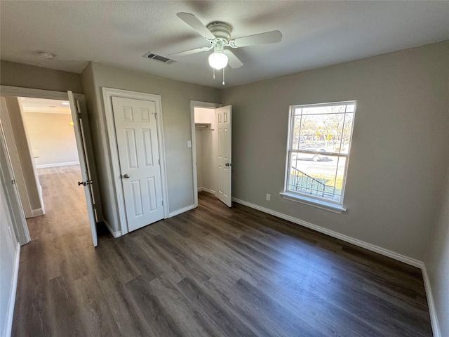 unfurnished bedroom featuring dark wood-type flooring, a textured ceiling, ceiling fan, and a closet