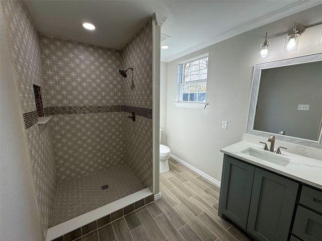 bathroom with vanity, tiled shower, ornamental molding, and toilet