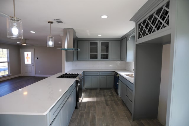 kitchen featuring stainless steel gas stove, decorative light fixtures, ventilation hood, and gray cabinets