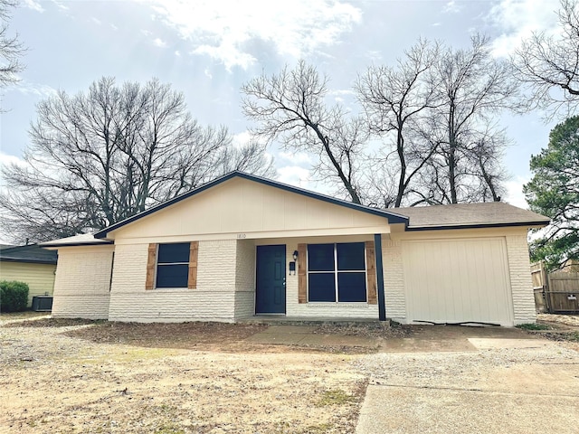 view of front of house with concrete driveway, brick siding, an attached garage, and central air condition unit