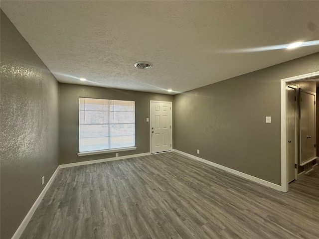 spare room with dark hardwood / wood-style floors and a textured ceiling