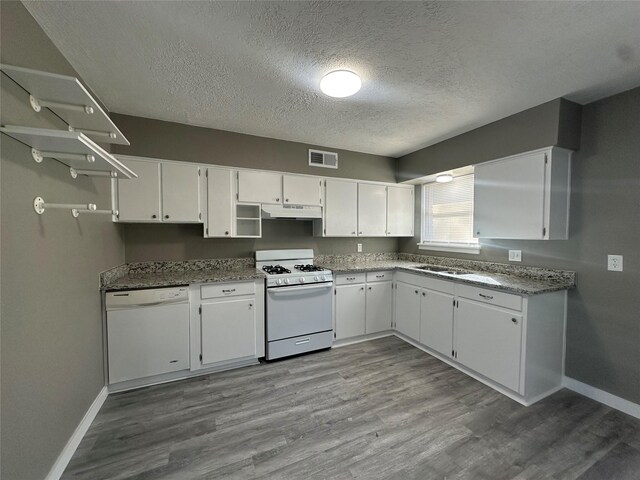 kitchen with white cabinetry, dark stone counters, a textured ceiling, white appliances, and hardwood / wood-style flooring