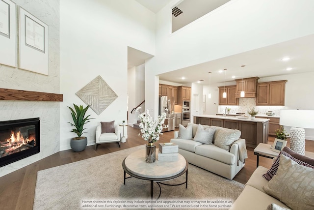 living room with sink, a high end fireplace, dark wood-type flooring, and a high ceiling