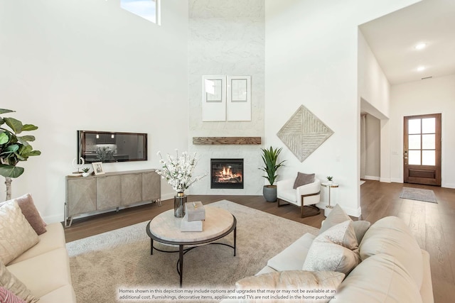 living room featuring a fireplace, a towering ceiling, and hardwood / wood-style flooring