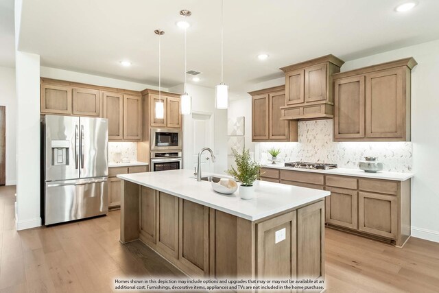 kitchen featuring pendant lighting, a kitchen island with sink, sink, appliances with stainless steel finishes, and light hardwood / wood-style floors