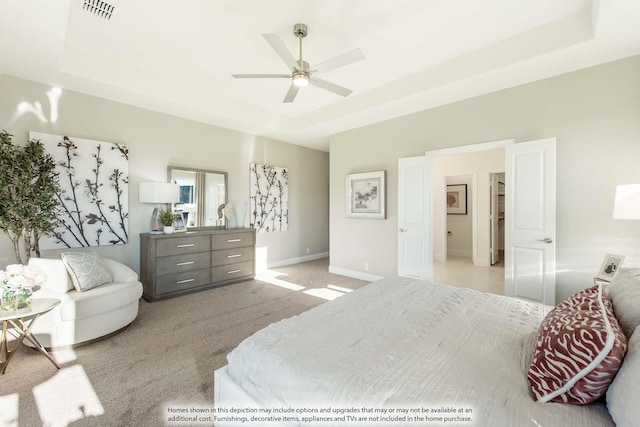 bedroom featuring ceiling fan, light colored carpet, and a tray ceiling