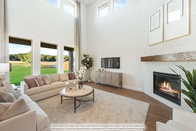 living room featuring hardwood / wood-style floors, a premium fireplace, and a high ceiling