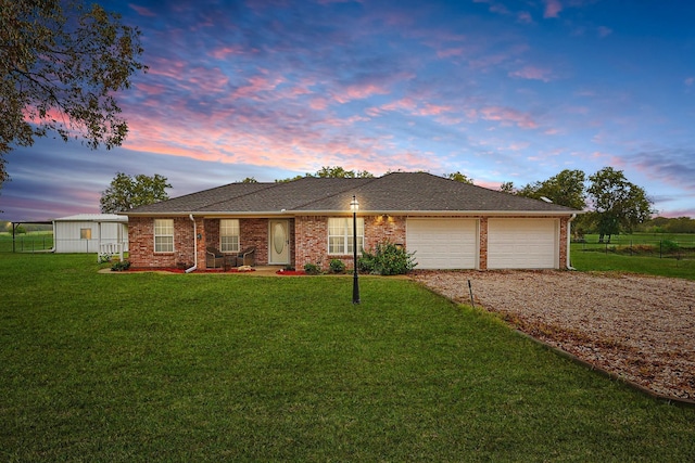 ranch-style home featuring a garage and a yard