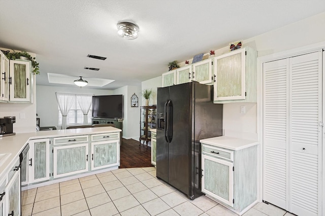 kitchen featuring black refrigerator with ice dispenser, white cabinets, and light tile patterned flooring