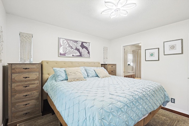 bedroom with ensuite bath, dark hardwood / wood-style floors, and a textured ceiling