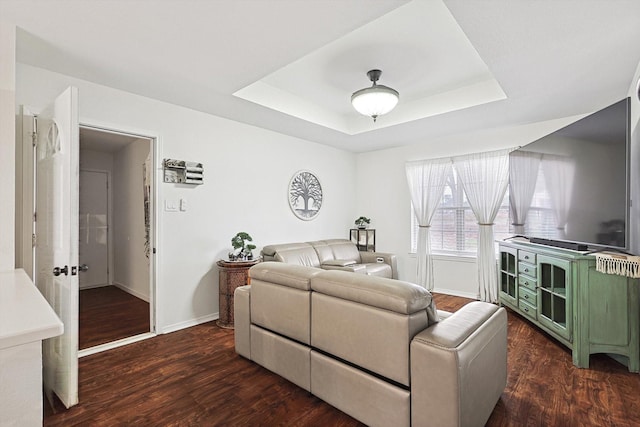 living room featuring a tray ceiling and dark hardwood / wood-style flooring