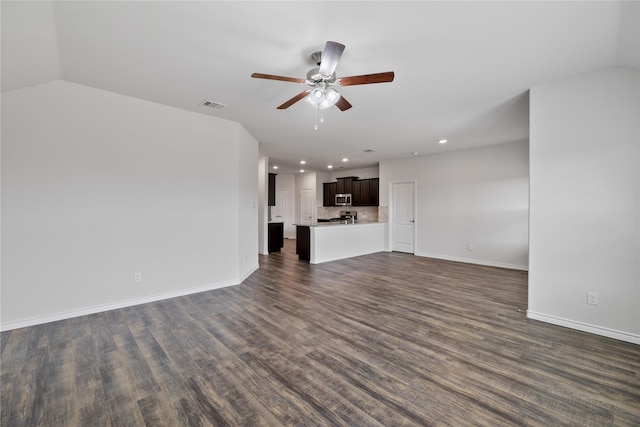 unfurnished living room featuring vaulted ceiling, dark hardwood / wood-style floors, and ceiling fan