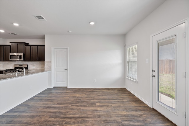 kitchen featuring dark wood-type flooring, stainless steel appliances, light stone countertops, and dark brown cabinets