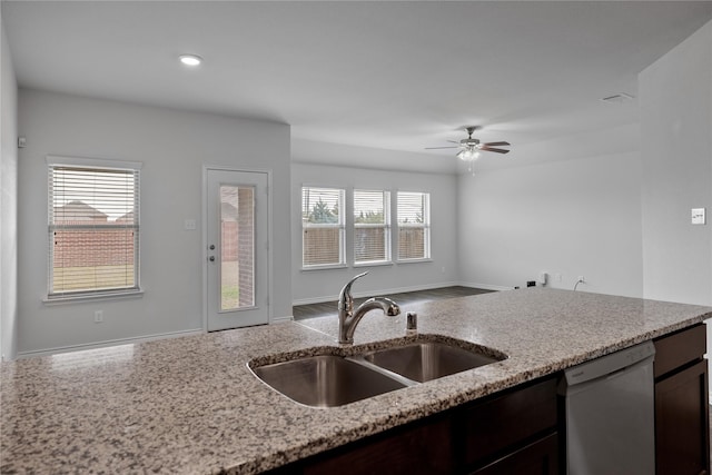 kitchen featuring light stone counters, dark brown cabinetry, white dishwasher, and sink