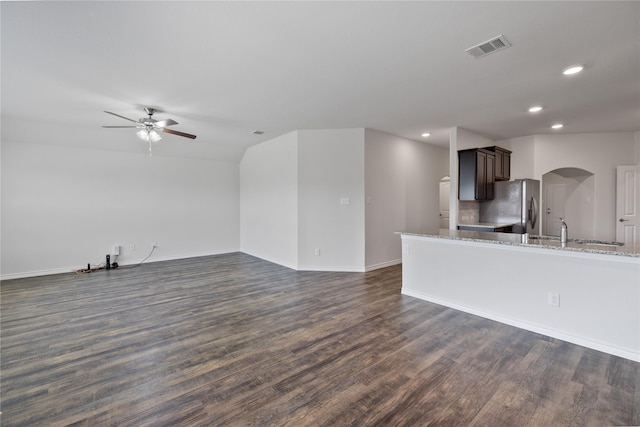 interior space featuring dark brown cabinetry, dark hardwood / wood-style floors, light stone countertops, and stainless steel refrigerator