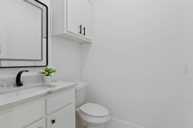 bathroom with toilet, baseboards, and vanity