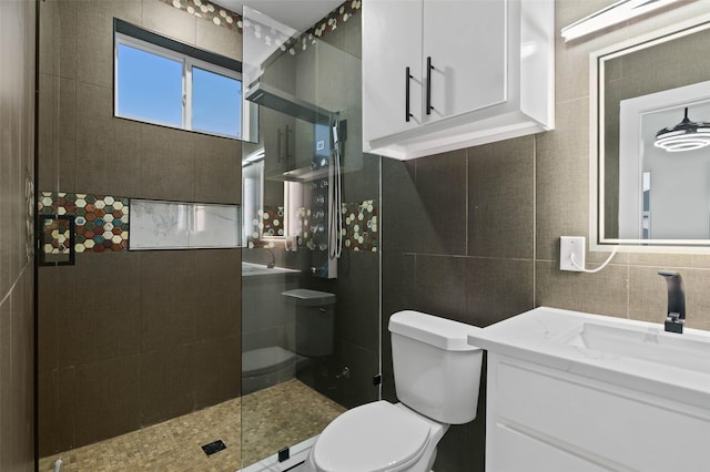 bathroom with tile walls, vanity, toilet, and walk in shower