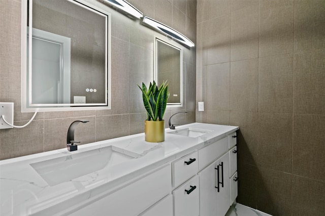 bathroom with double vanity, a sink, and tile walls