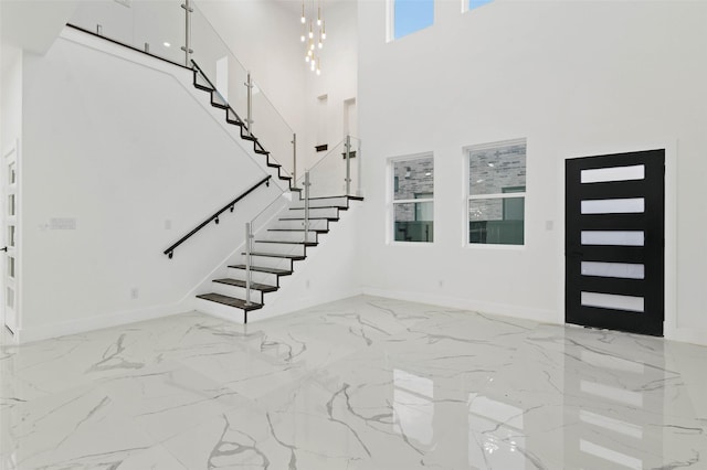 entrance foyer featuring stairs, marble finish floor, a high ceiling, and baseboards