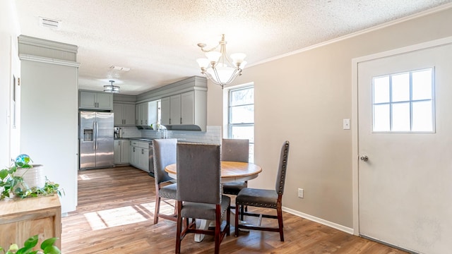 dining room featuring a textured ceiling, crown molding, a chandelier, and dark hardwood / wood-style floors