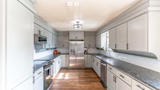 kitchen featuring a textured ceiling, decorative backsplash, sink, and stainless steel appliances