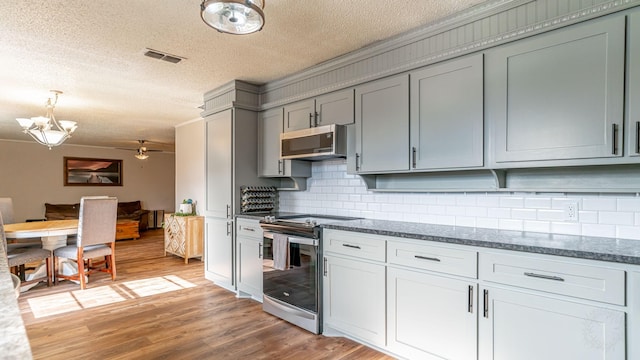 kitchen featuring ceiling fan, stainless steel appliances, light hardwood / wood-style flooring, a textured ceiling, and decorative backsplash