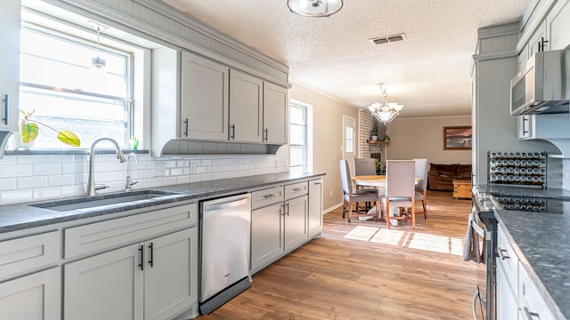 kitchen featuring a textured ceiling, decorative light fixtures, sink, and stainless steel appliances