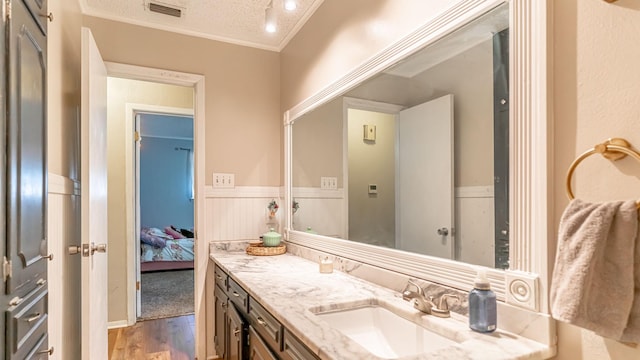 bathroom featuring vanity, hardwood / wood-style floors, a textured ceiling, and crown molding