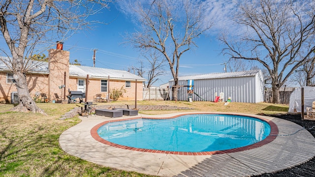 view of pool featuring a lawn, a grill, and an outbuilding