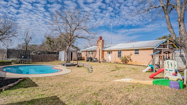 view of pool with a playground, a trampoline, a storage unit, and a lawn