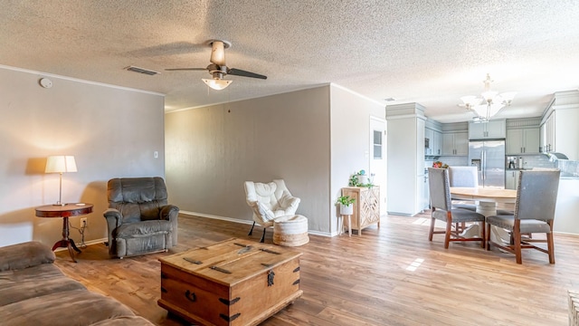 living room featuring ceiling fan with notable chandelier, ornamental molding, a textured ceiling, and light hardwood / wood-style flooring